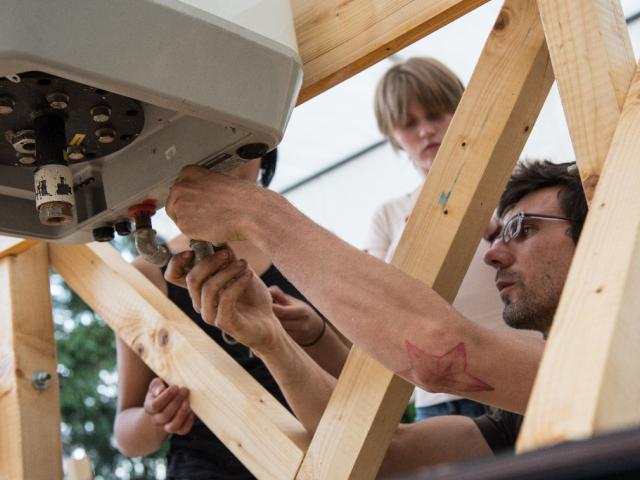 Am Wasserspeicher werden die Zufuhrrohre installiert Wasserspeicher am Gestell der Solardusche angebaut
