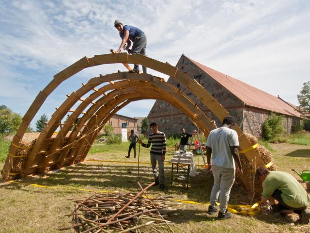 Nachdem die Holzkonstruktion steht, werden erste Strohballen aufgeschichtet. | Foto: Hendrik Silbermann (ARTWORKs) Nachdem die Holzkonstruktion steht, werden erste Strohballen aufgeschichtet. | Foto: Hendrik Silbermann (ARTWORKs)