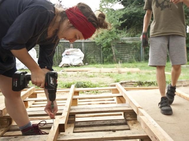 Holzarbeiten | Foto: Hendrik Silbermann (ARTWORKs) Eine junge Frau benutzt den Akkuschrauber aus Holz für das Seitenteil der Komposttoilette.| Foto: Hendrik Silbermann (ARTWORKs)
