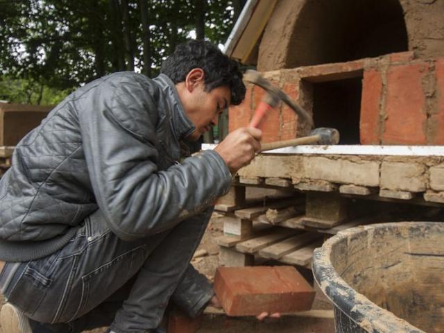Zertrümmern eines Ziegelsteins für den Lehmbackofen. | Foto: Hendrik Silbermann (ARTWORKs) Jugendlicher beim Zertrümmern eines Ziegelsteins für den Lehmbackofen. | Foto: Hendrik Silbermann (ARTWORKs)