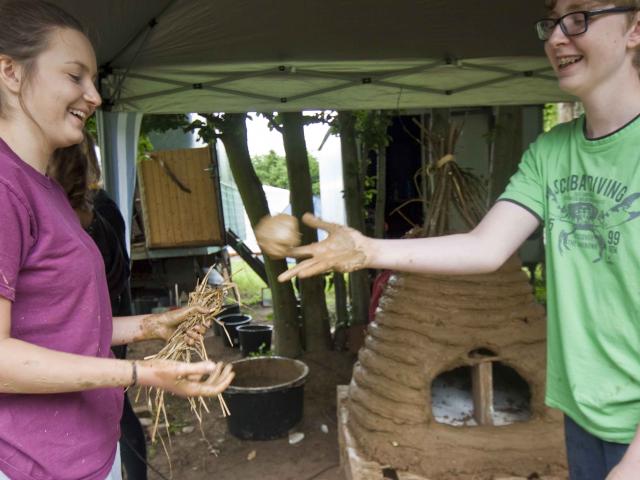 Spaß mit Lehm. | Foto: Hendrik Silbermann (ARTWORKs) Zwei Teilnehmende werfen sich Lehm zu. | Foto: Hendrik Silbermann (ARTWORKs)