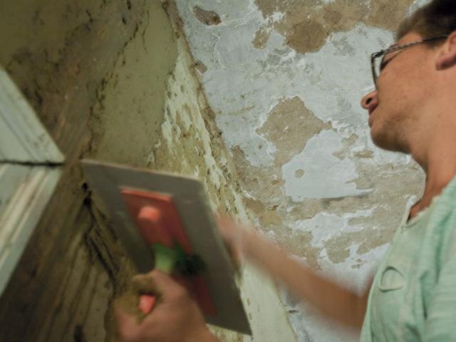 Alle Wände werden verputzt. | Foto: Hendrik Silbermann (ARTWORKs) Ein Teilnehmender steht an einer Wand und verputzt diese. | Foto: Hendrik Silbermann (ARTWORKs)