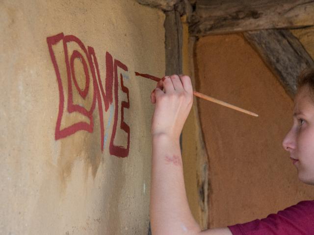 Die Bushaltestelle wird mit Inschriften versehen. | Foto: Hendrik Silbermann (ARTWORKs) Die Bushaltestelle wird mit Inschriften versehen. Ein Mädchen malt die Buchstaben "Love" an die Wand. | Foto: Hendrik Silbermann (ARTWORKs)