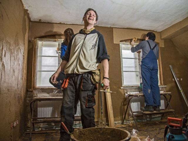Gemeinschaftlich wird der Innenraum verputzt. | Foto: Hendrik Silbermann (ARTWORKs) Die Teilnehmenden arbeiten im Raum an verschiedenen Wänden sowie an den Fenstern. | Foto: Hendrik Silbermann (ARTWORKs)
