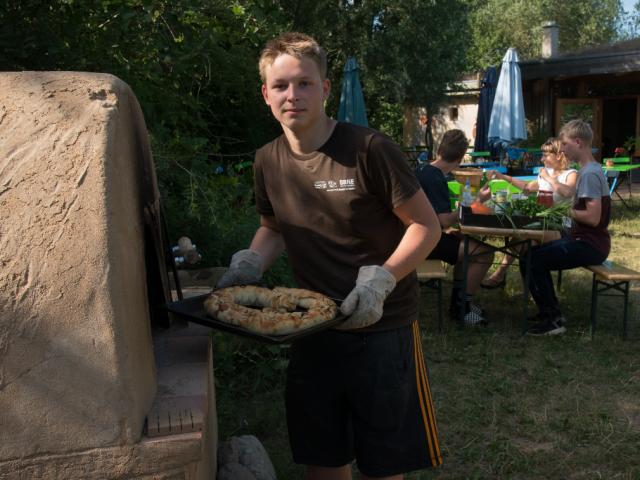 Voilá! Das mit Mozarella gefüllte Brot kommt frisch aus dem Lehmbackofen. |Foto: Hendrik Silbermann (ARTWORKs) Backen im Lehmbackofen. |Foto: Hendrik Silbermann (ARTWORKs)