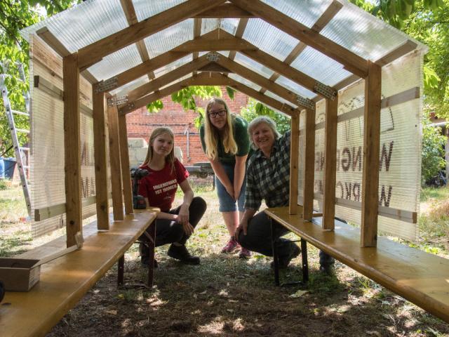 Das Dach für den Gewölbeofen ist fertig! |Foto: Hendrik Silbermann (ARTWORKs) Teilnehmerinnen stehen unter ihrem Bauergebnis: ein Dach für den Gewölbeofen. |Foto: Hendrik Silbermann (ARTWORKs)