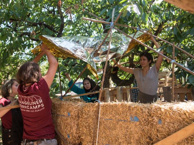 Bauen einer Notunterkunft. | Foto: Hendrik Silbermann (ARTWORKs) Bauen einer Notunterkunft durch Upcycling-Teilnehmende aus Strohballen, Rettungsdecke und weiteren Materialien. | Foto: Hendrik Silbermann (ARTWORKs)