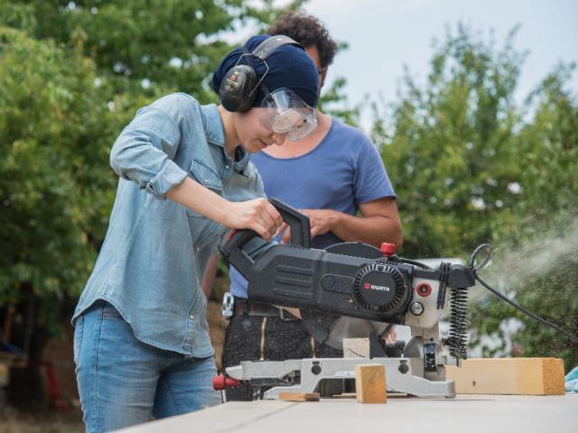 Die Arbeit mit Maschinen wurde geübt. | Foto: Hendrik Silbermann (ARTWORks) Eine Teilnehmerin bearbeitet mit einer Maschine und Schutzbrille Holz. | Foto: Hendrik Silbermann (ARTWORks)