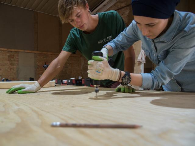 Holzarbeiten. | Foto: Hendrik Silbermann (ARTWORKs) Zwei Teilnehmende bohren Löcher in ein Holzbrett. | Foto: Hendrik Silbermann (ARTWORKs)